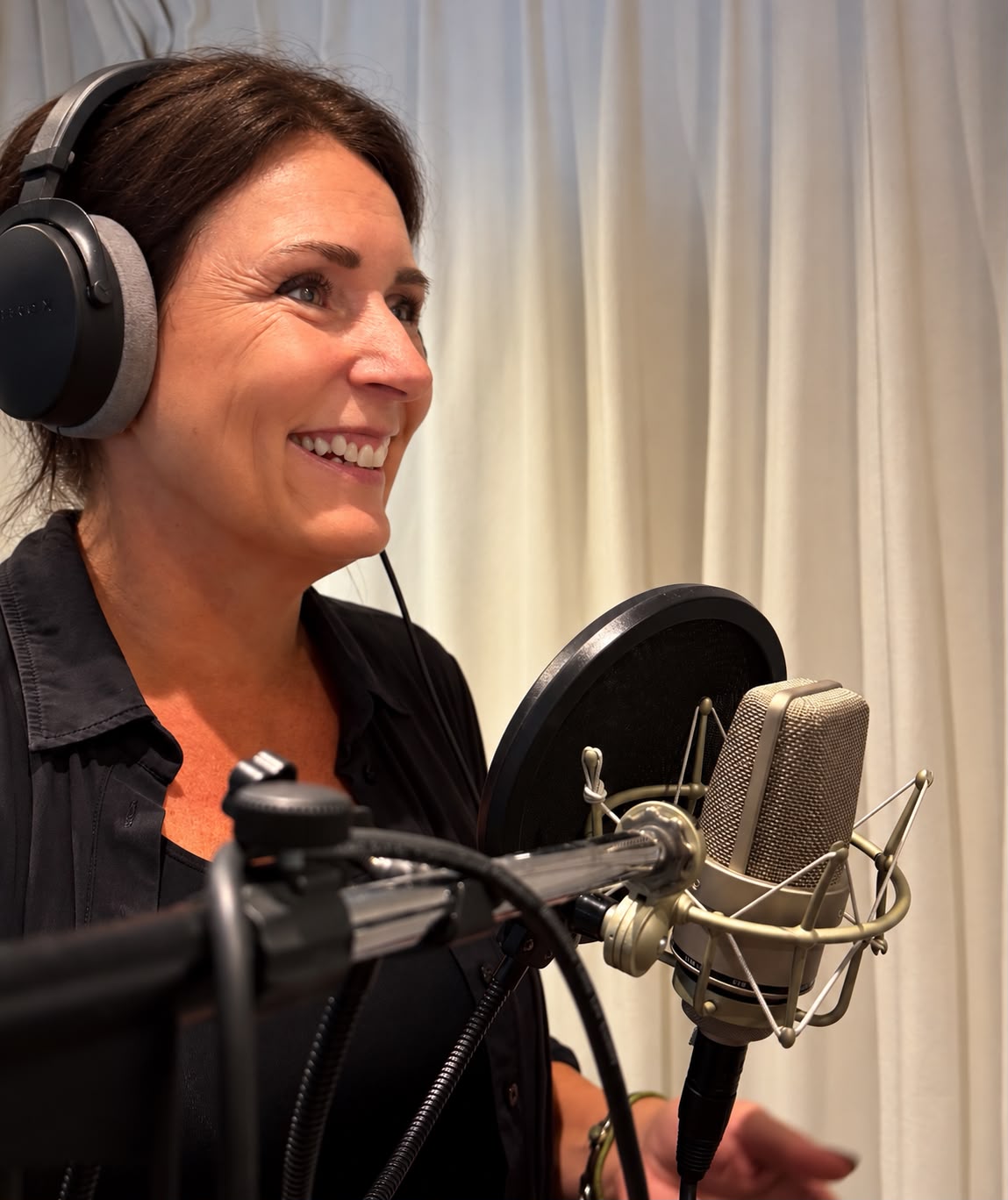 Marieke de Ruiter, voice-over en stemacteur, lachend met koptelefoon achter een studiomicrofoon